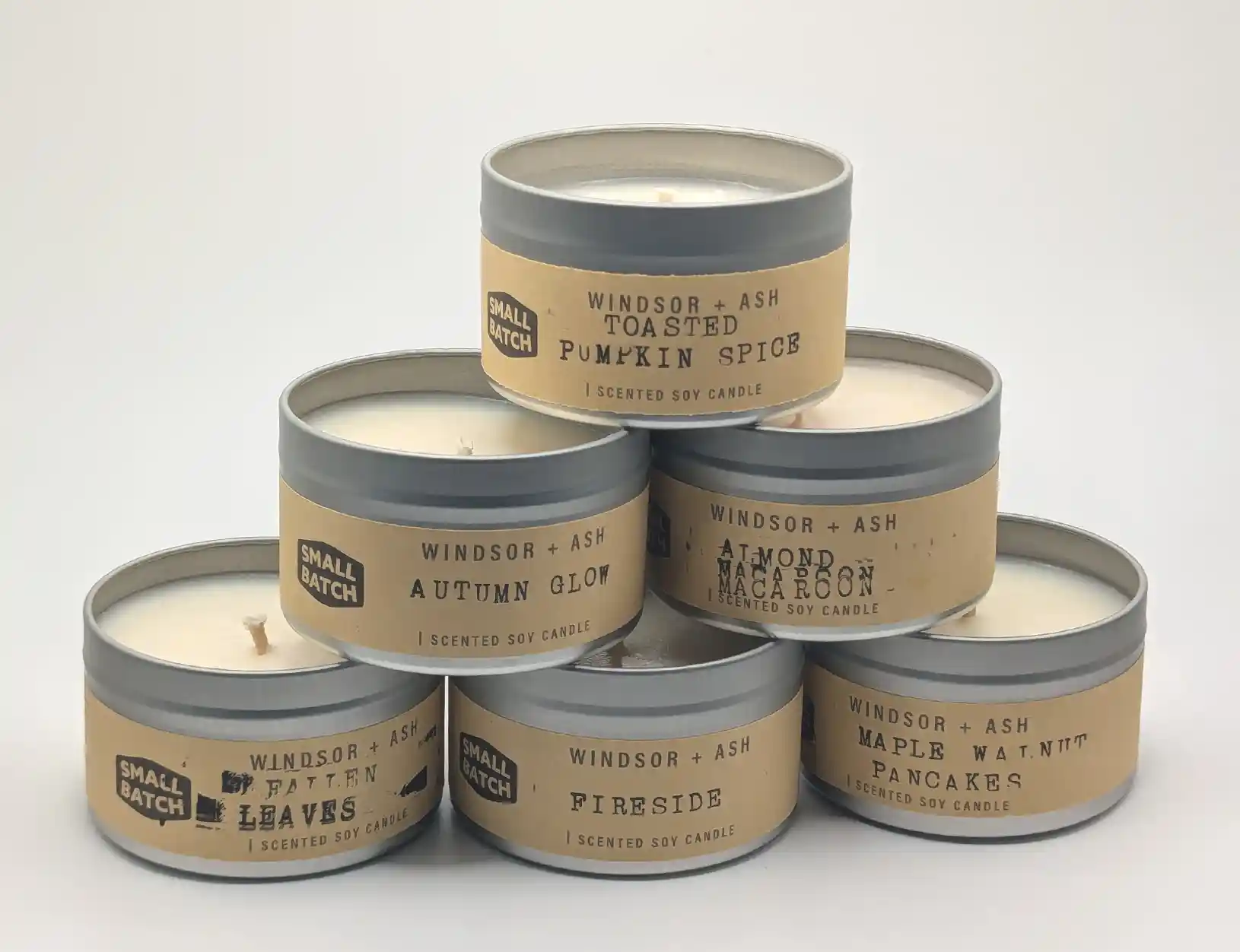 Six Windsor + Ash scented Small Batch soy candles in silver tins with tan kraft paper label. Featuring Toasted Pumpkin Spice, Autumn Glow, Almond Macaron, Fallen Leaves, Fireside, and Maple Walnut Pancakes scents.