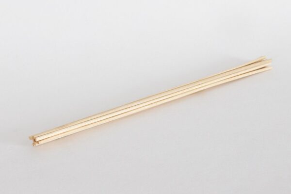Set of natural rattan reed diffuser sticks laid flat on a white background.